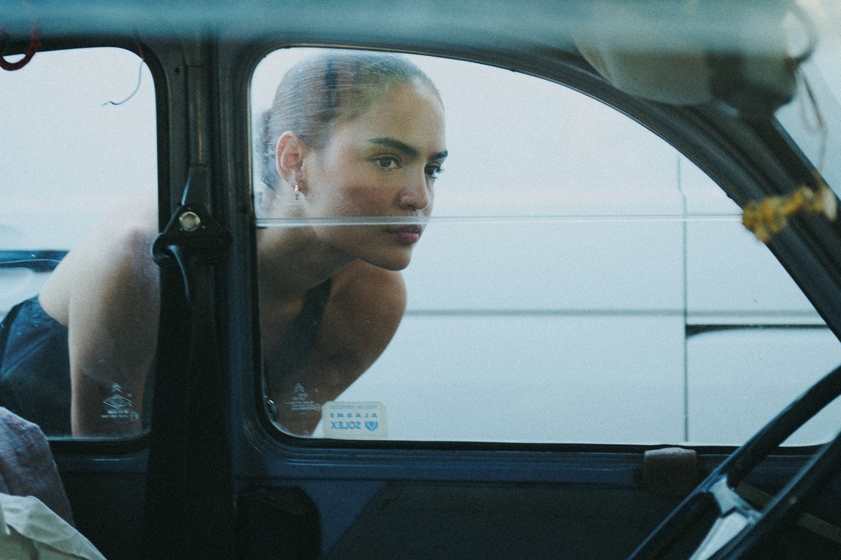 Editorial portrait of a woman seen through a car window.
