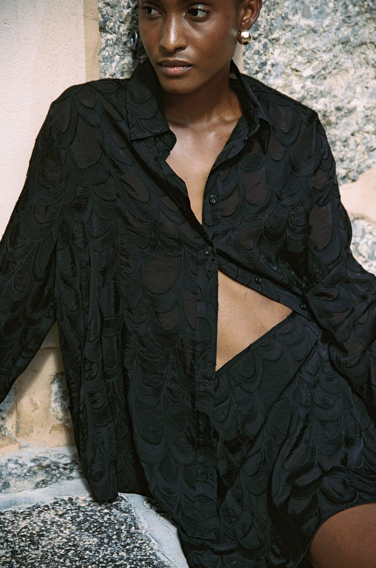 Model wearing the AUDĒRE. Rae wrap mini skirt in Black, close-up of the textured matching set.