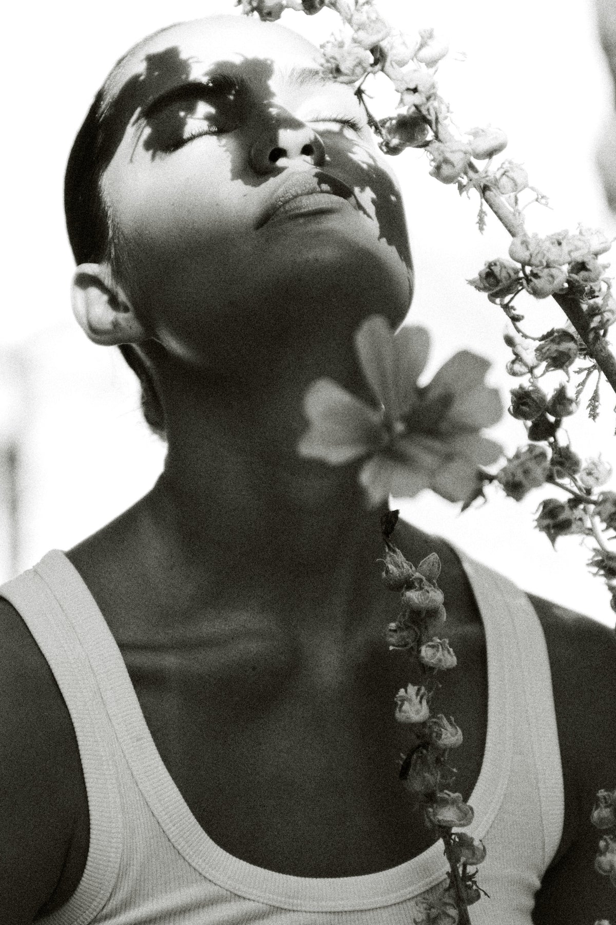 Black-and-white editorial portrait of a model holding flowers.