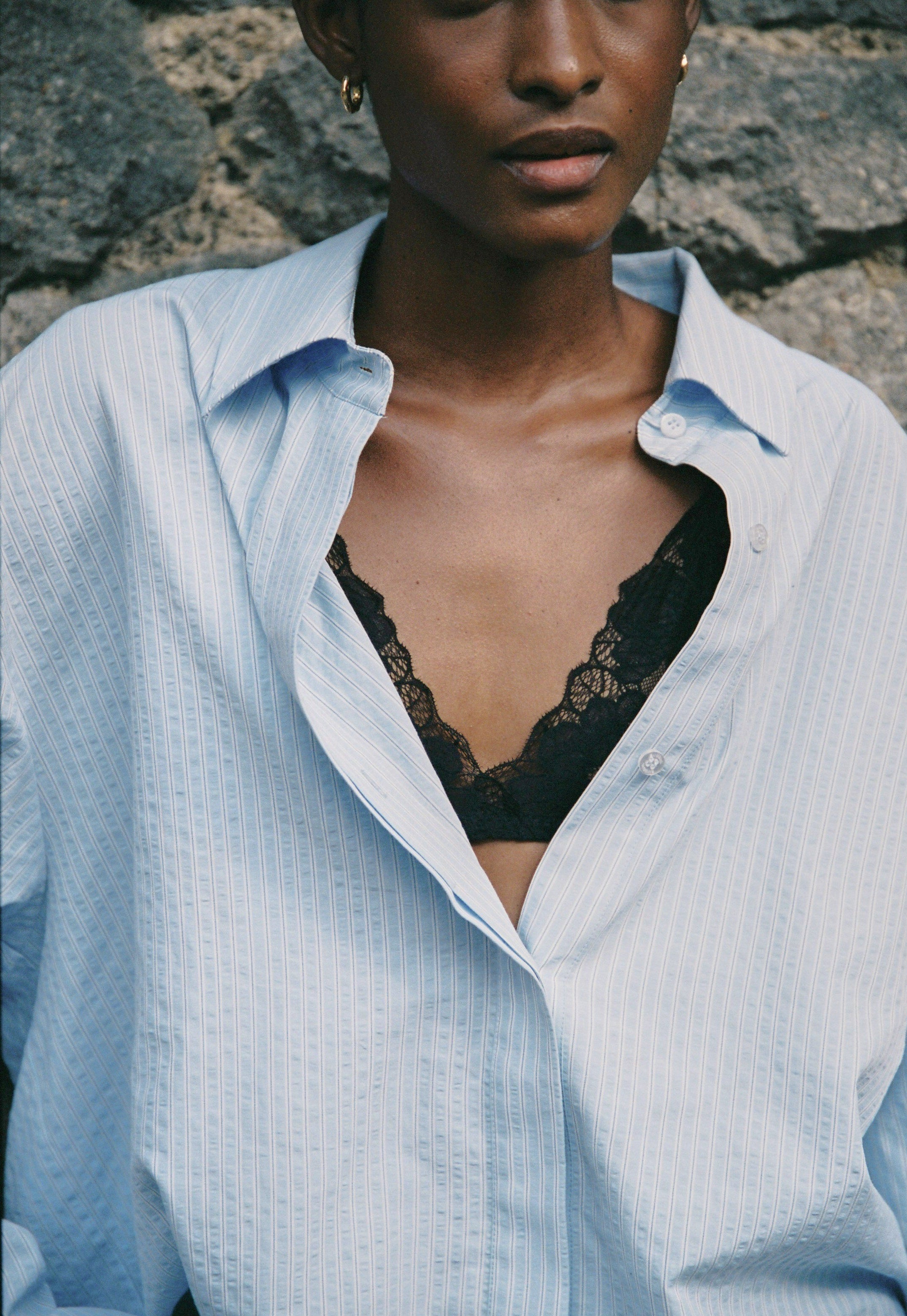 Model wearing the AUDĒRE. Alba oversized striped shirt in Ciel blue, close-up of the striped fabric and collar.