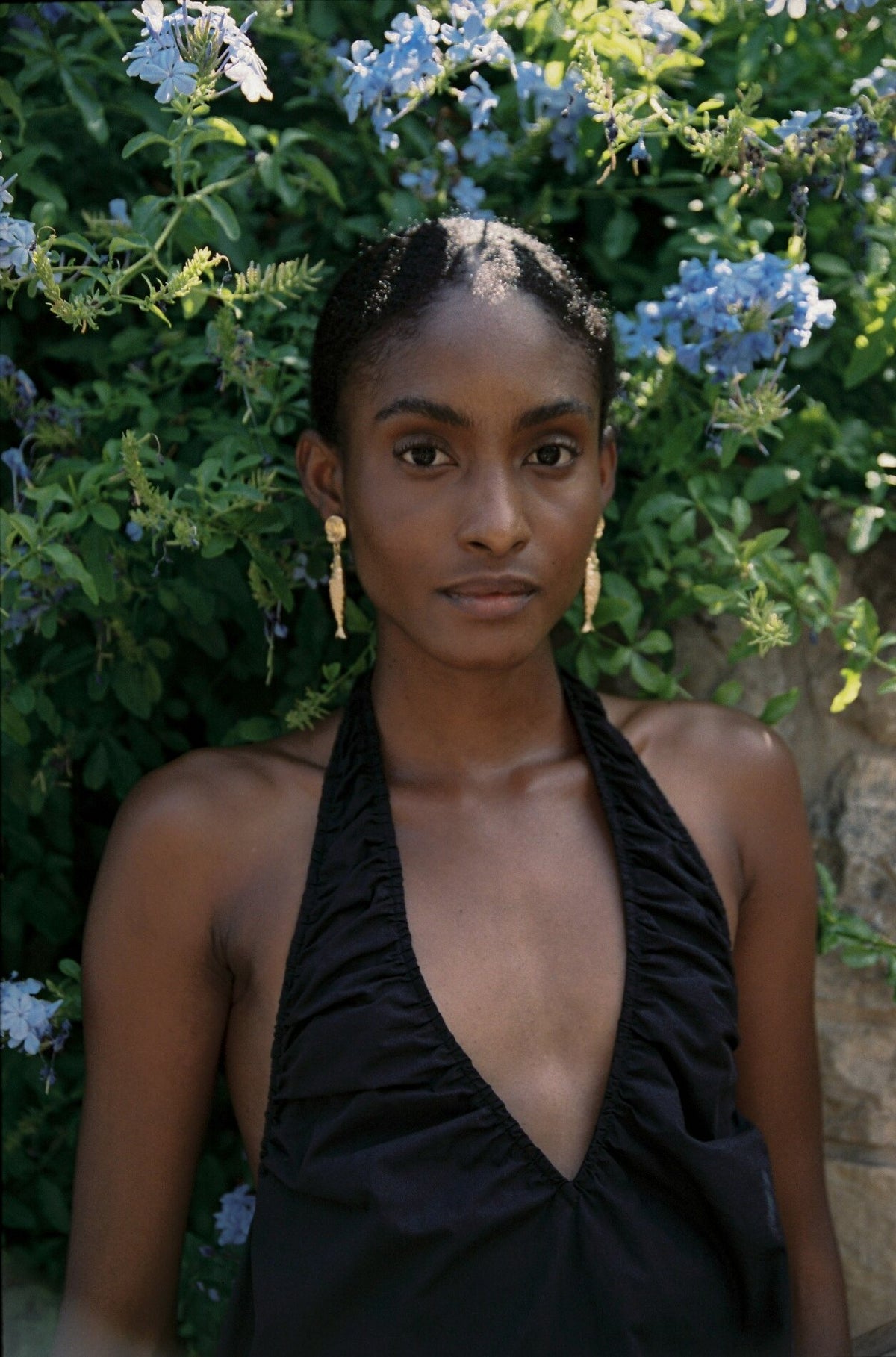 Model wearing the AUDĒRE. Azura cotton halter mini dress in Black, close-up of the halter neckline.