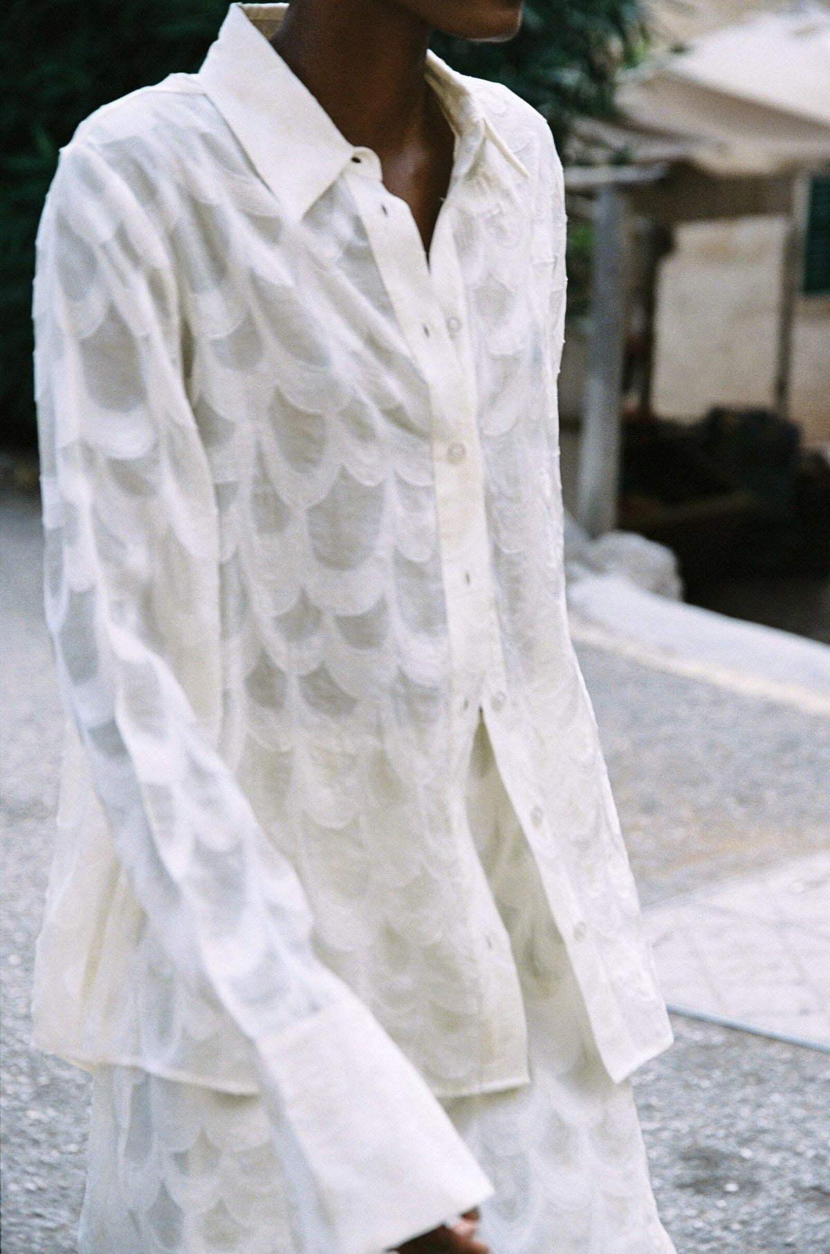 Model wearing the AUDĒRE. Rae semi-sheer shirt in Ivory, close-up of the textured shirt fabric.