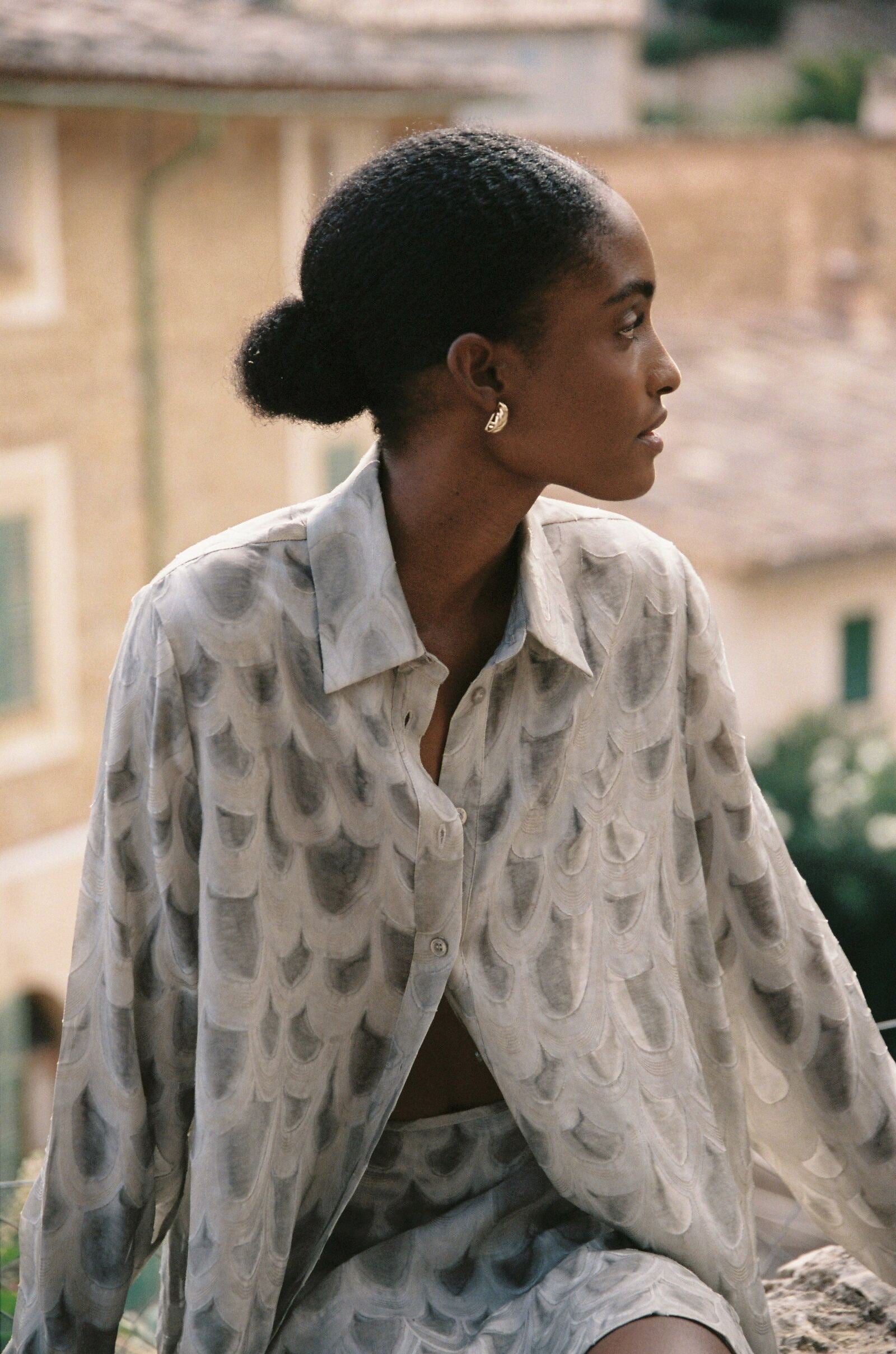 Model wearing the AUDĒRE. Rae semi-sheer shirt in Dove, close-up of the collar and textured fabric.