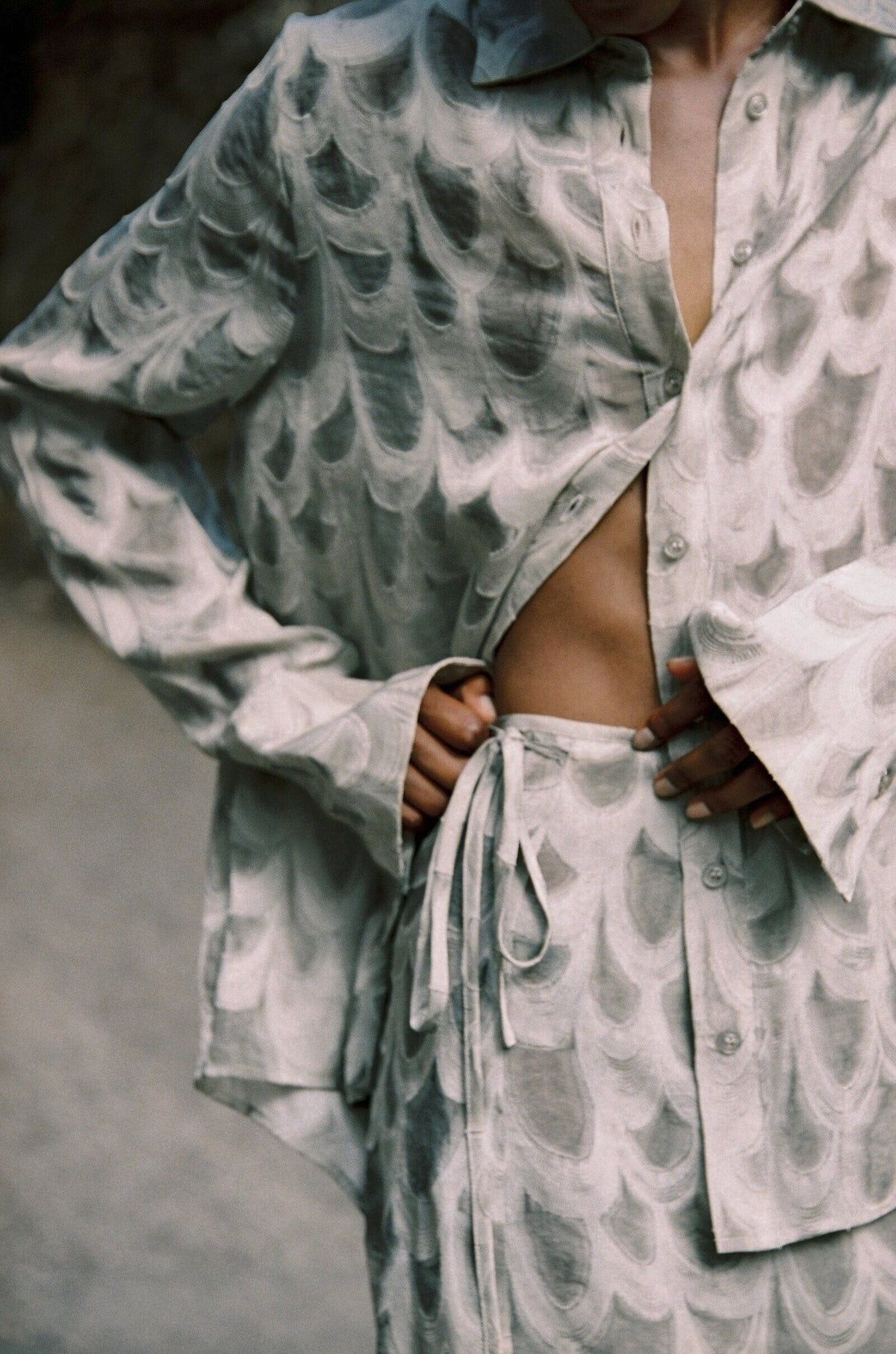 Model wearing the AUDĒRE. Rae wrap mini skirt in Dove, close-up of the adjustable wrap tie.